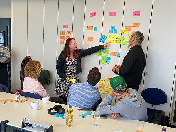 Facilitating a design thinking workshop with participants using sticky notes on a wall.