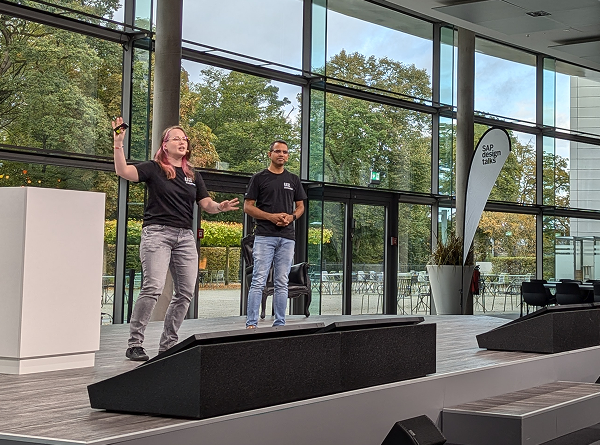 Presenting on stage at a UX event, speaking to an audience alongside a co-presenter.